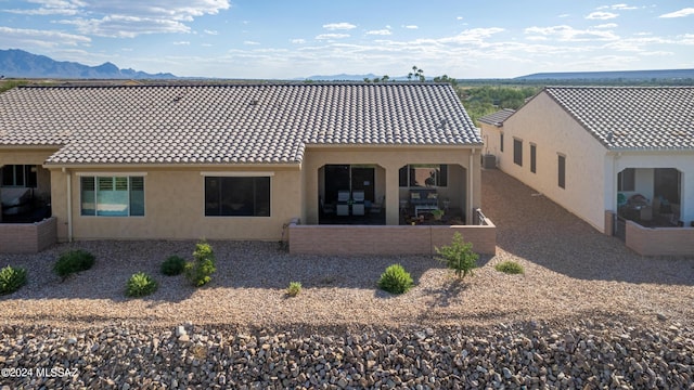 rear view of house with a tile roof, a mountain view, and stucco siding