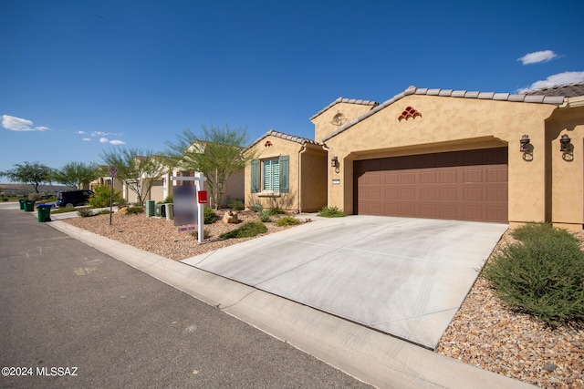 mediterranean / spanish-style house featuring an attached garage, a tiled roof, concrete driveway, and stucco siding