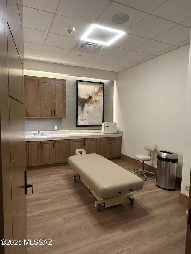 interior space featuring visible vents, a paneled ceiling, light wood-style flooring, and baseboards