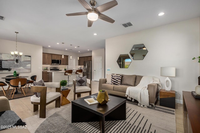 living area with light tile patterned floors, recessed lighting, visible vents, and ceiling fan with notable chandelier