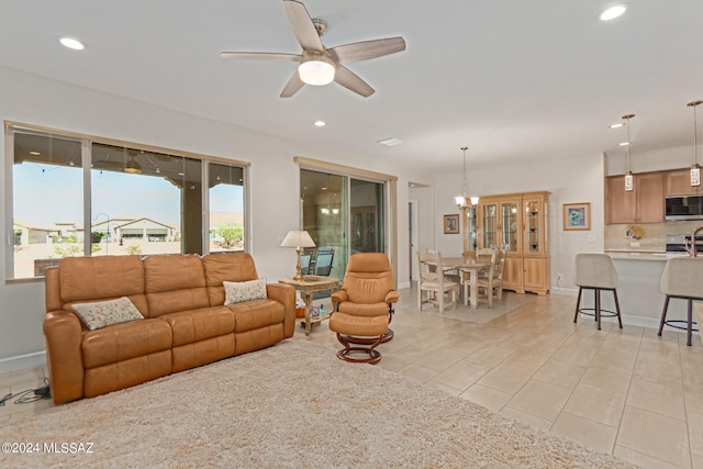 living room with ceiling fan with notable chandelier and light tile patterned floors