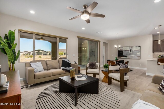 living room with ceiling fan with notable chandelier and light tile patterned floors