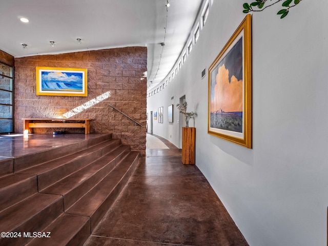 corridor featuring concrete flooring and vaulted ceiling