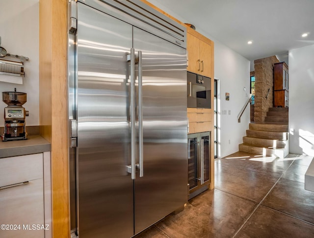 kitchen with stainless steel built in fridge, beverage cooler, finished concrete floors, light brown cabinets, and recessed lighting