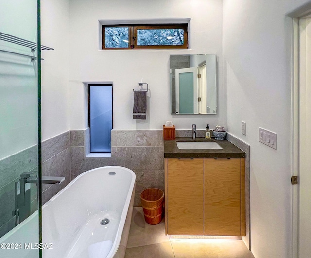 bathroom featuring a tub to relax in, tile patterned floors, vanity, and tile walls