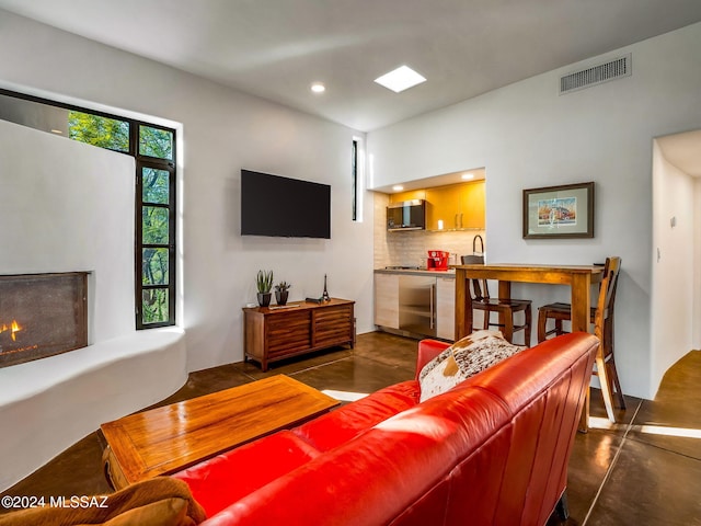 living room with finished concrete flooring, recessed lighting, and a warm lit fireplace
