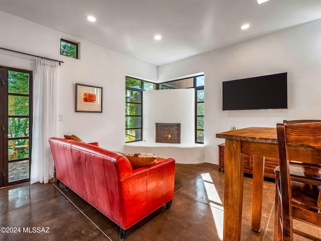 living area with finished concrete flooring, recessed lighting, and a lit fireplace