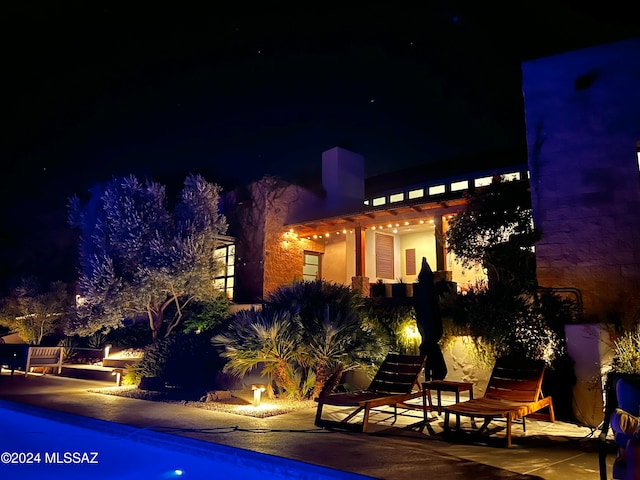 pool at night featuring a patio