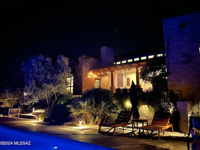 pool at twilight featuring an outdoor pool and a patio