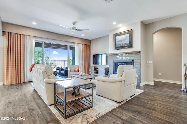 living room featuring hardwood / wood-style flooring, ceiling fan, and a fireplace