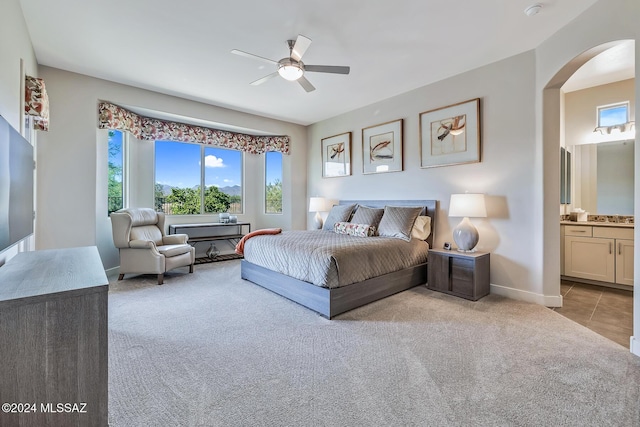 bedroom with light carpet, connected bathroom, and ceiling fan