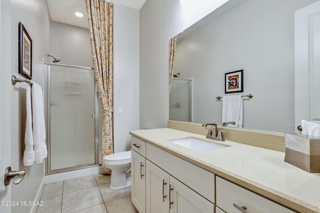 bathroom featuring tile patterned floors, vanity, a shower with shower door, and toilet