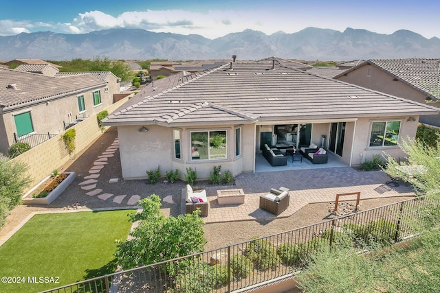 rear view of property with a patio area, a mountain view, and an outdoor living space with a fire pit