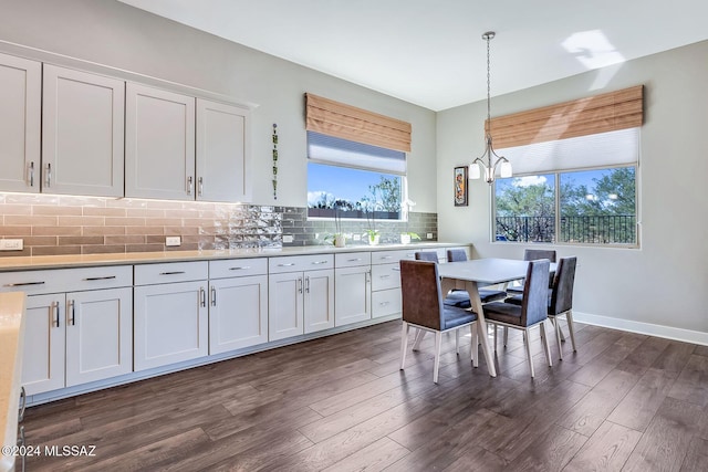 kitchen with pendant lighting, dark hardwood / wood-style floors, tasteful backsplash, a notable chandelier, and white cabinetry