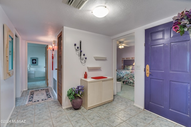 tiled entryway with ceiling fan and a textured ceiling