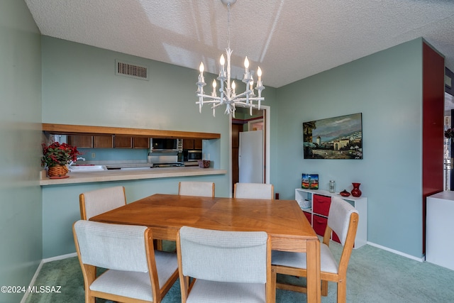 dining space featuring light carpet, a notable chandelier, and a textured ceiling