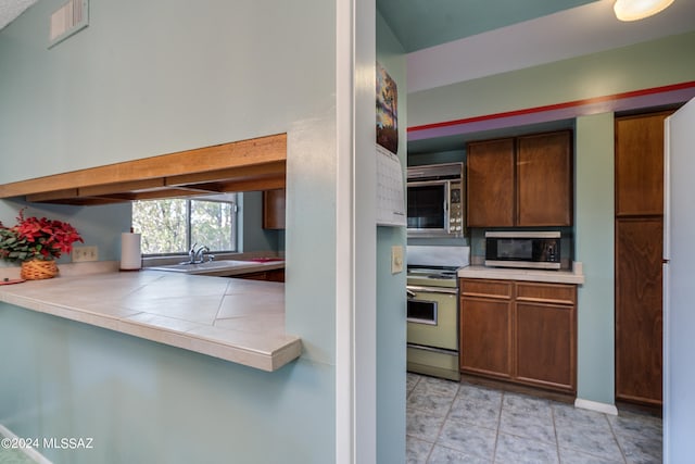 kitchen with stainless steel appliances, sink, and light tile patterned floors