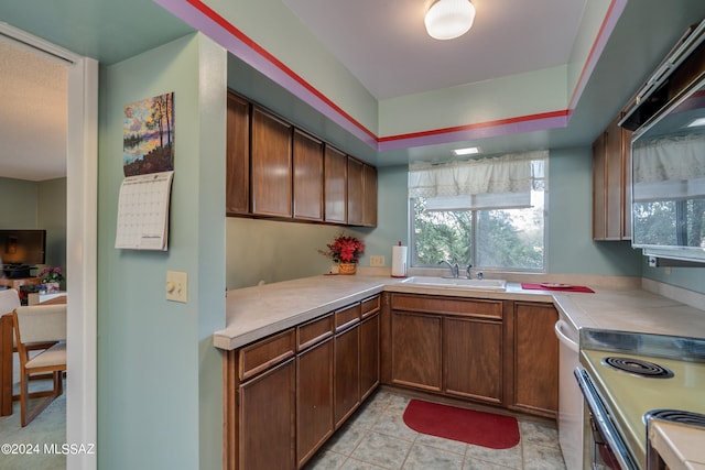 kitchen with light tile patterned floors, appliances with stainless steel finishes, sink, and kitchen peninsula