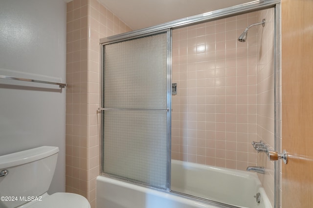 bathroom featuring combined bath / shower with glass door and toilet