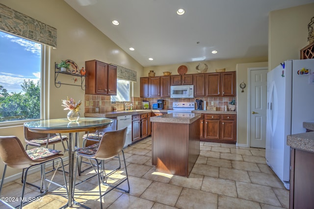 kitchen with white appliances, a center island, plenty of natural light, and tasteful backsplash