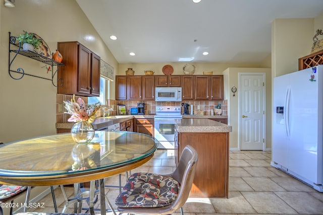 kitchen featuring lofted ceiling, sink, white appliances, backsplash, and a center island