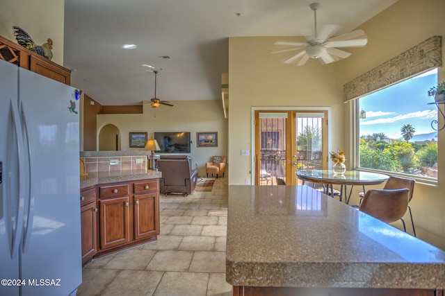 kitchen with ceiling fan, a kitchen breakfast bar, white fridge, and a center island