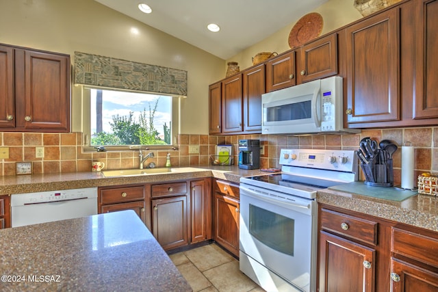 kitchen with lofted ceiling, sink, white appliances, and tasteful backsplash