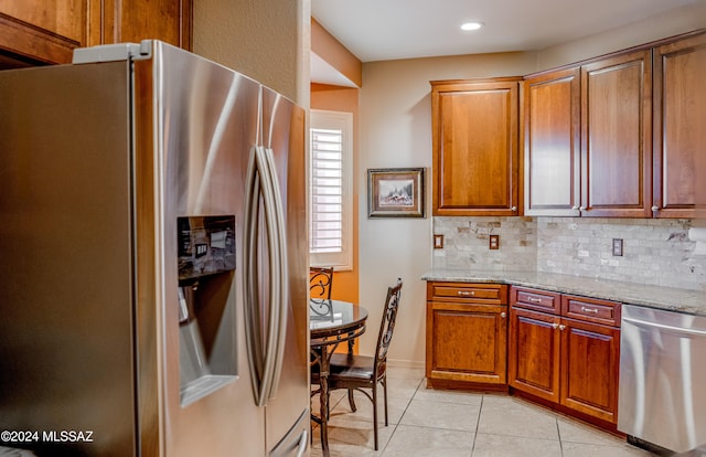 kitchen featuring light stone countertops, backsplash, stainless steel appliances, and light tile patterned flooring