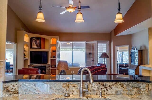 kitchen featuring a fireplace, built in shelves, pendant lighting, and sink