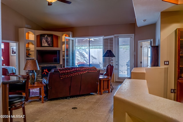 living room with ceiling fan, a fireplace, light tile patterned floors, and lofted ceiling