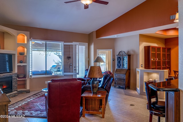 tiled living room featuring vaulted ceiling, ceiling fan, and a stone fireplace