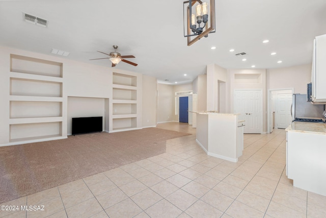 kitchen with light stone countertops, white cabinetry, ceiling fan, built in features, and light carpet