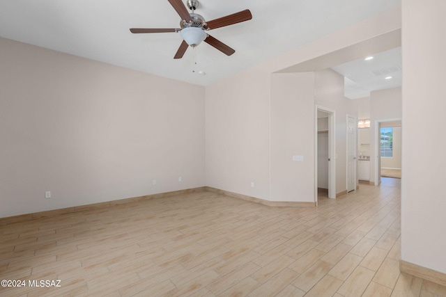 empty room with ceiling fan and light hardwood / wood-style flooring