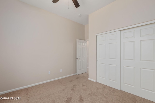 unfurnished bedroom with light colored carpet, a closet, and ceiling fan