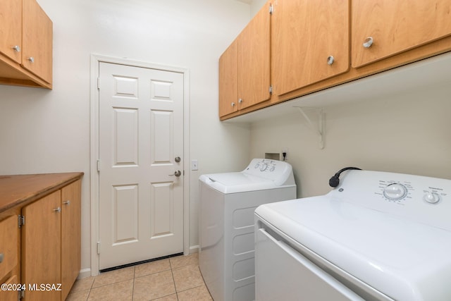 laundry area with washer and dryer, light tile patterned floors, and cabinets