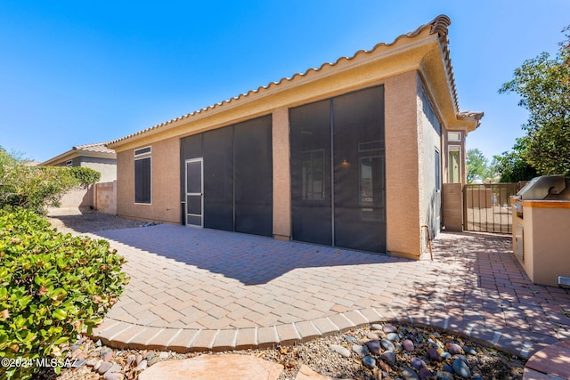 rear view of property featuring a patio and a sunroom