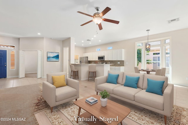 living room featuring ceiling fan with notable chandelier and light tile patterned flooring