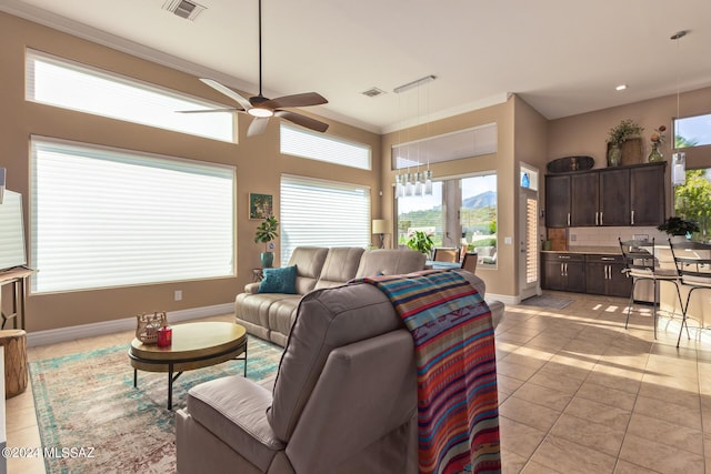 living room with crown molding, light tile patterned floors, a ceiling fan, visible vents, and baseboards