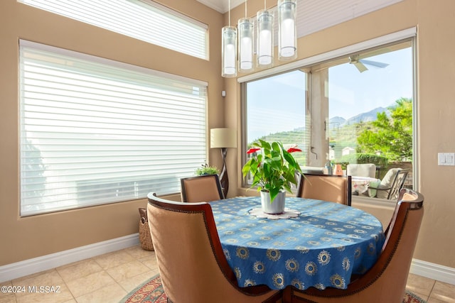 dining room featuring a mountain view, light tile patterned floors, baseboards, and ceiling fan