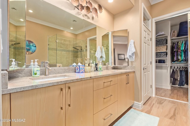 full bath featuring crown molding, double vanity, a sink, and a stall shower