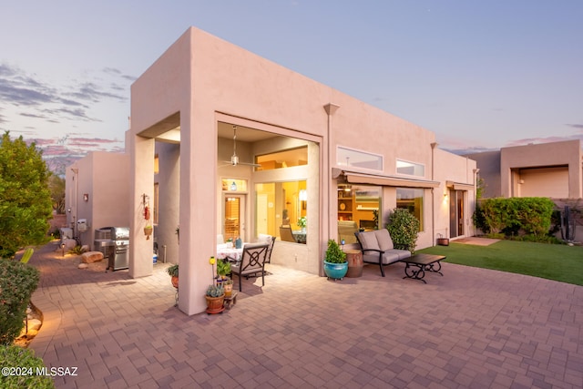 back house at dusk with a patio area