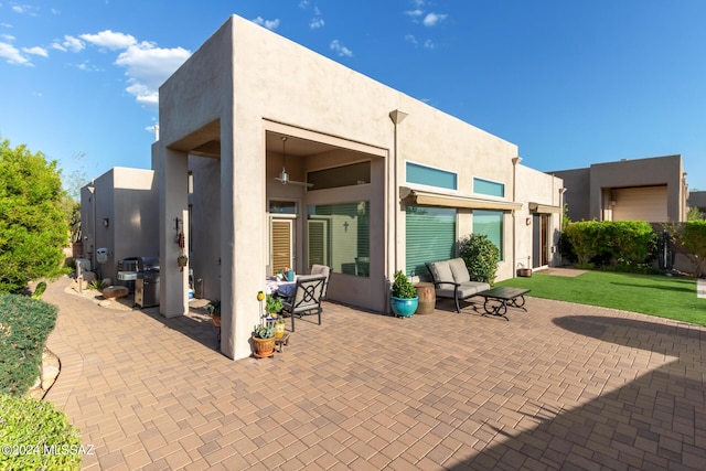 back of house with a patio, stucco siding, and a lawn