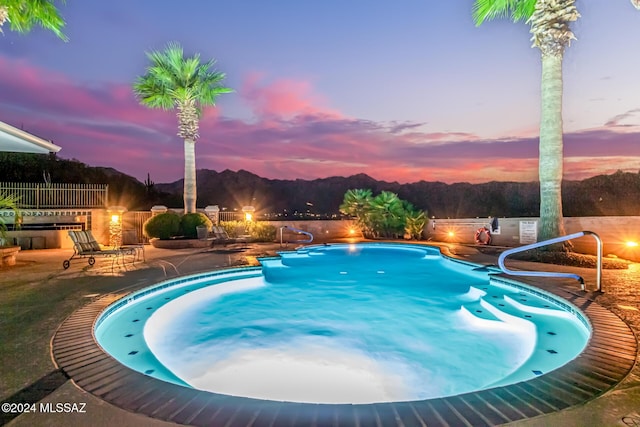 pool at dusk featuring a patio area and fence