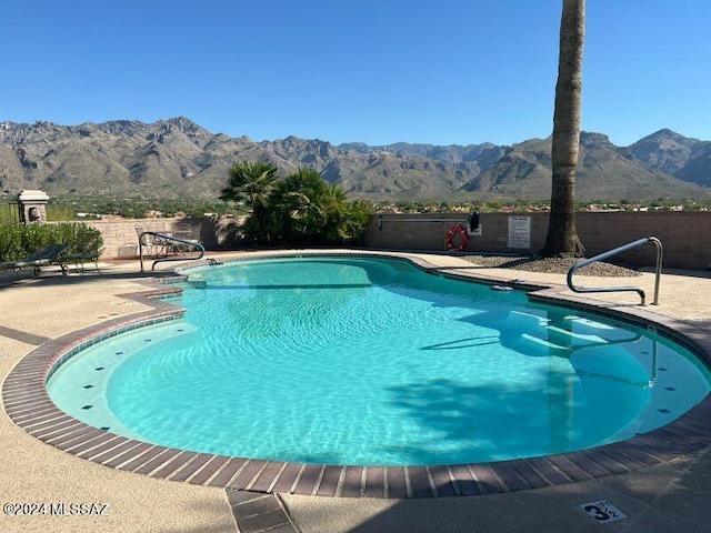 pool featuring a mountain view, fence, and a patio area