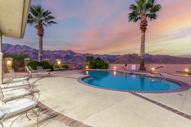 pool at dusk featuring a patio area and a mountain view