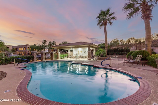 pool at dusk with a patio, a community pool, and fence