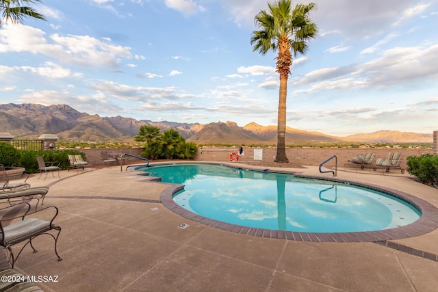 community pool with a patio, a mountain view, and fence