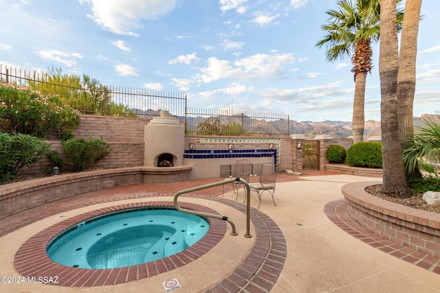 view of pool with exterior fireplace, an in ground hot tub, fence, and a patio