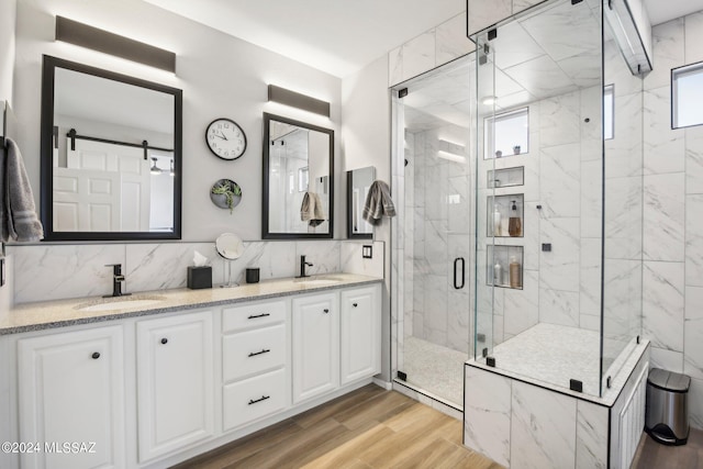 bathroom with vanity, hardwood / wood-style flooring, walk in shower, and tasteful backsplash