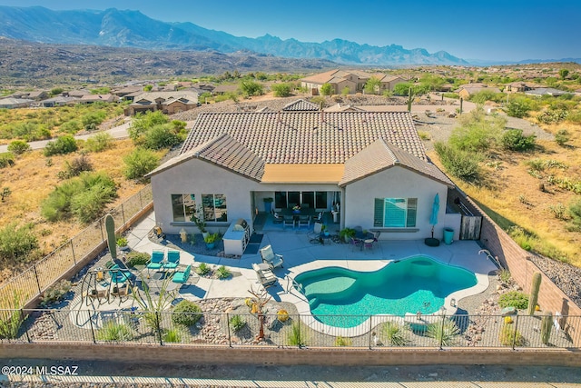 exterior space featuring a mountain view, a patio area, and a fenced in pool